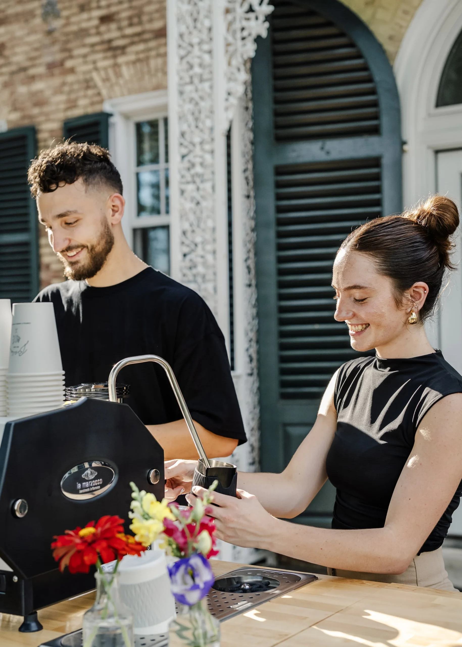 Professional baristas serving espresso from a mobile coffee cart at an event.