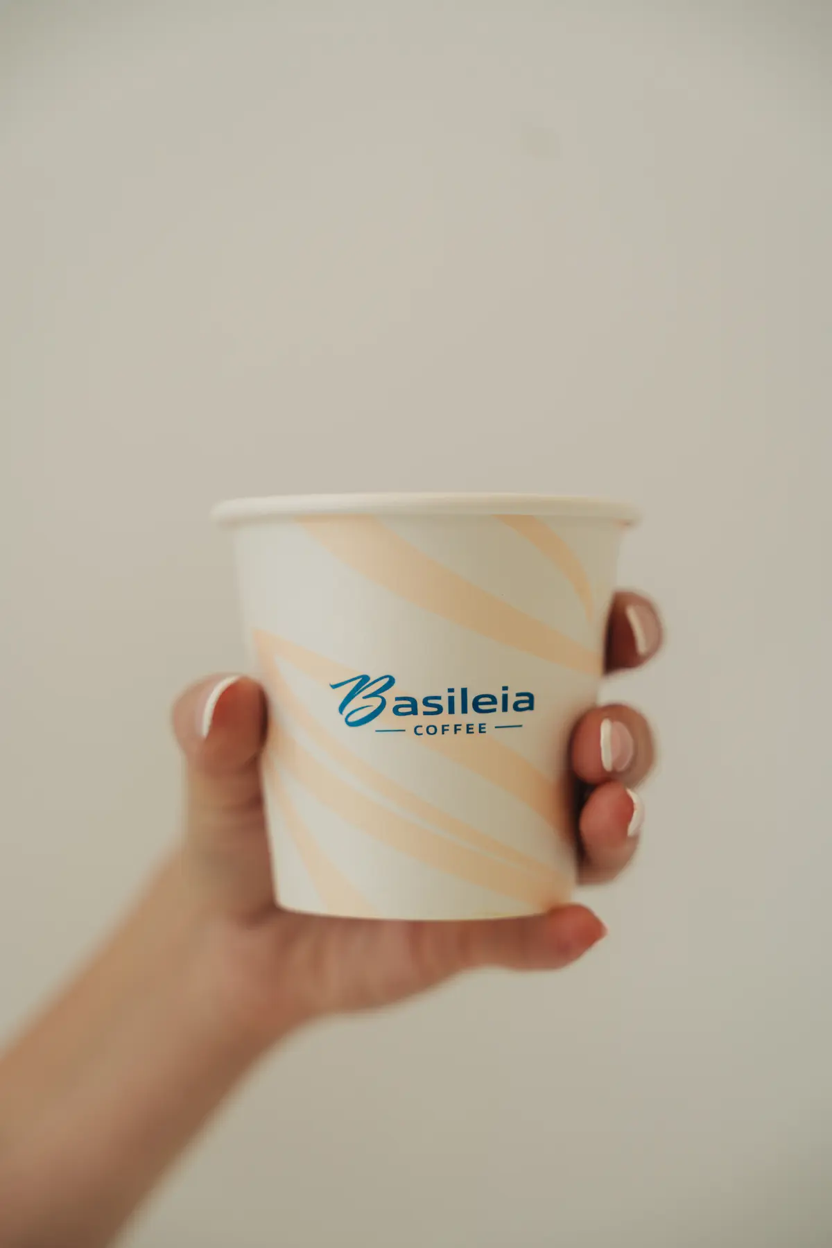Hand holding a Basileia Coffee branded cup